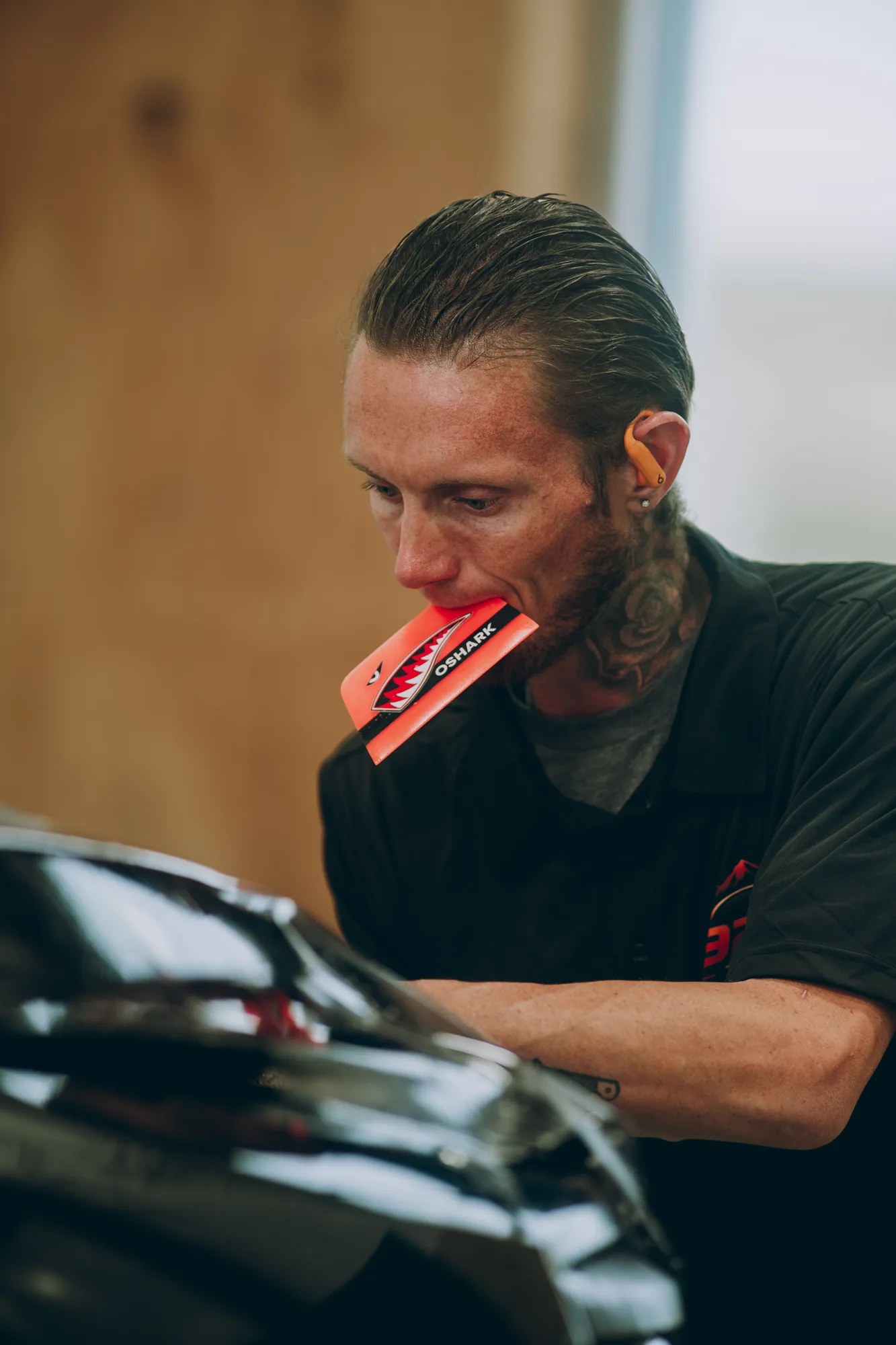 Window tint installer working a squeegee across a windshield, Canon FD 300mm f/2.8 on a Sony A1