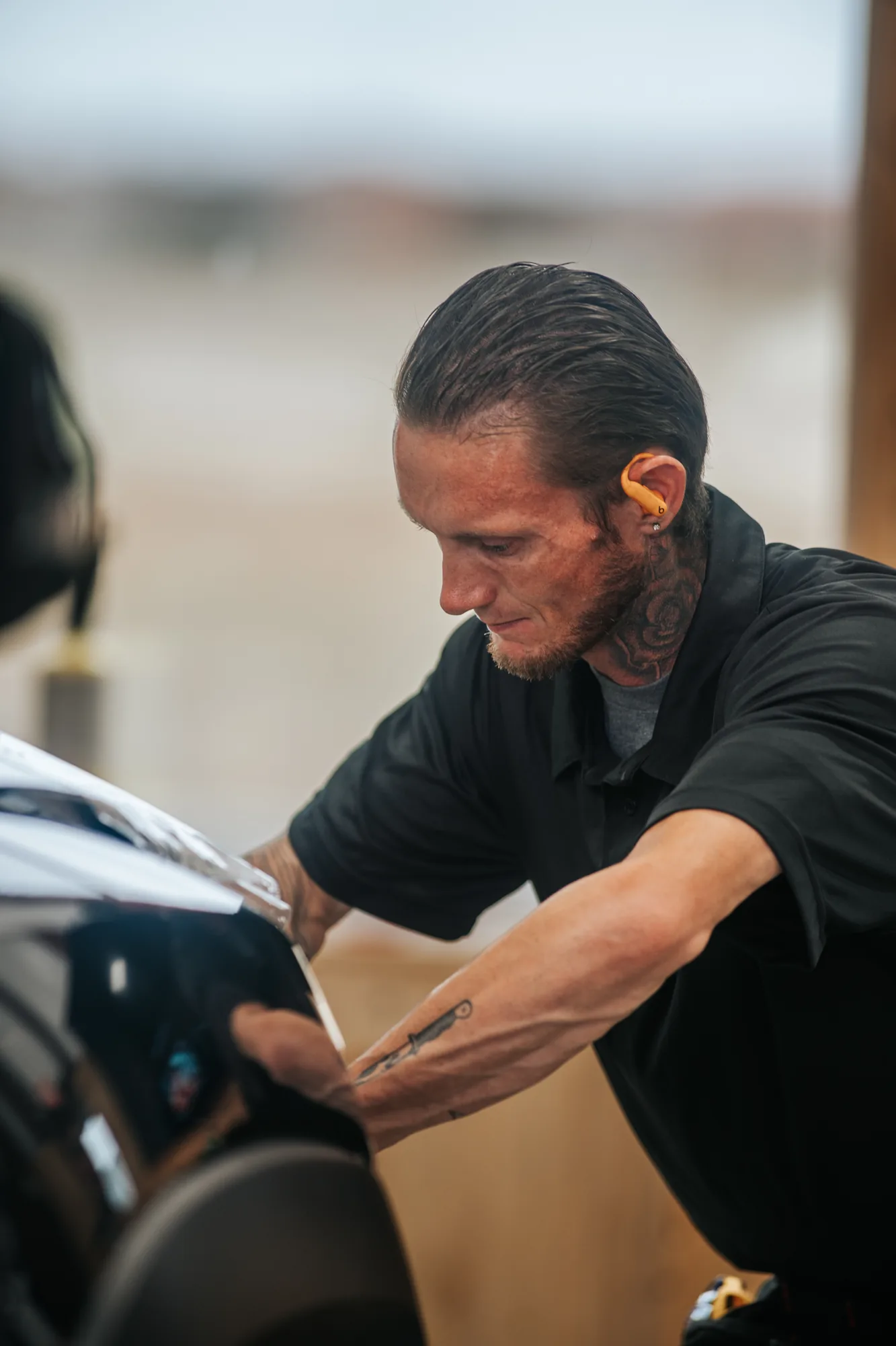 Installer leaning into a truck door, the 300mm lens flattening the shop behind him