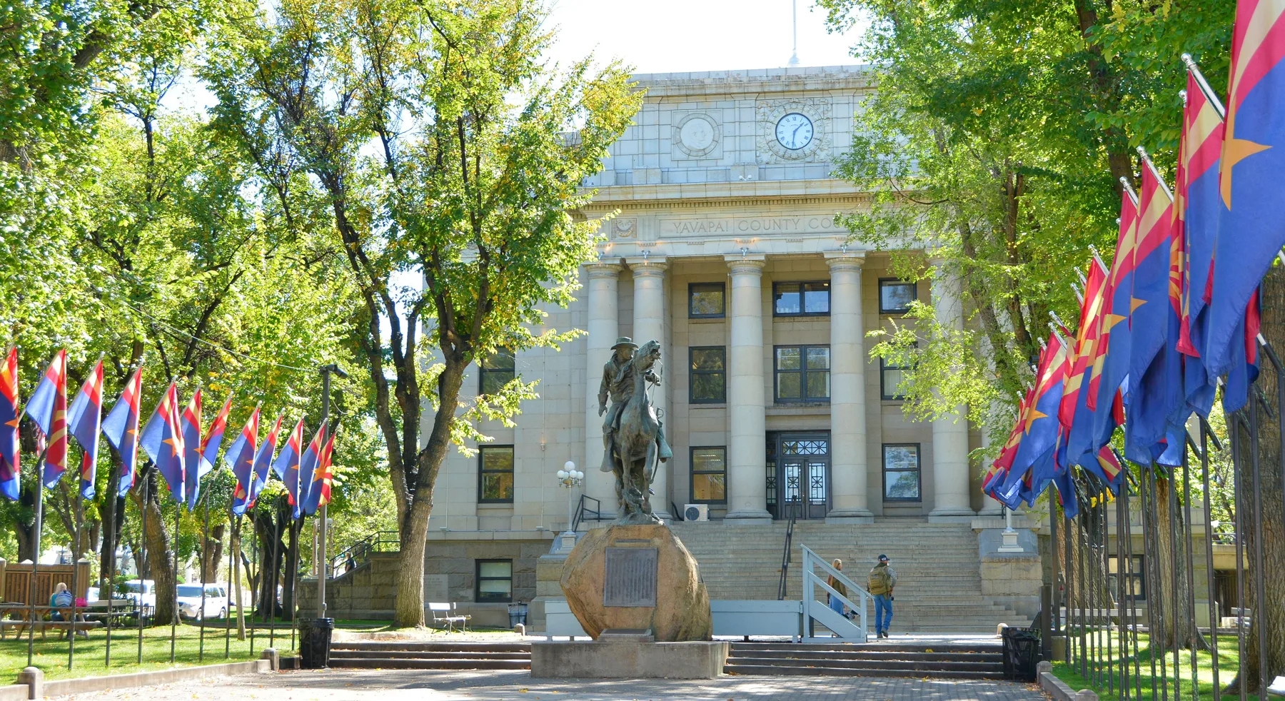 The Yavapai County Courthouse on Courthouse Plaza in downtown Prescott, Arizona, with the Bucky O'Neill statue and Arizona flags
