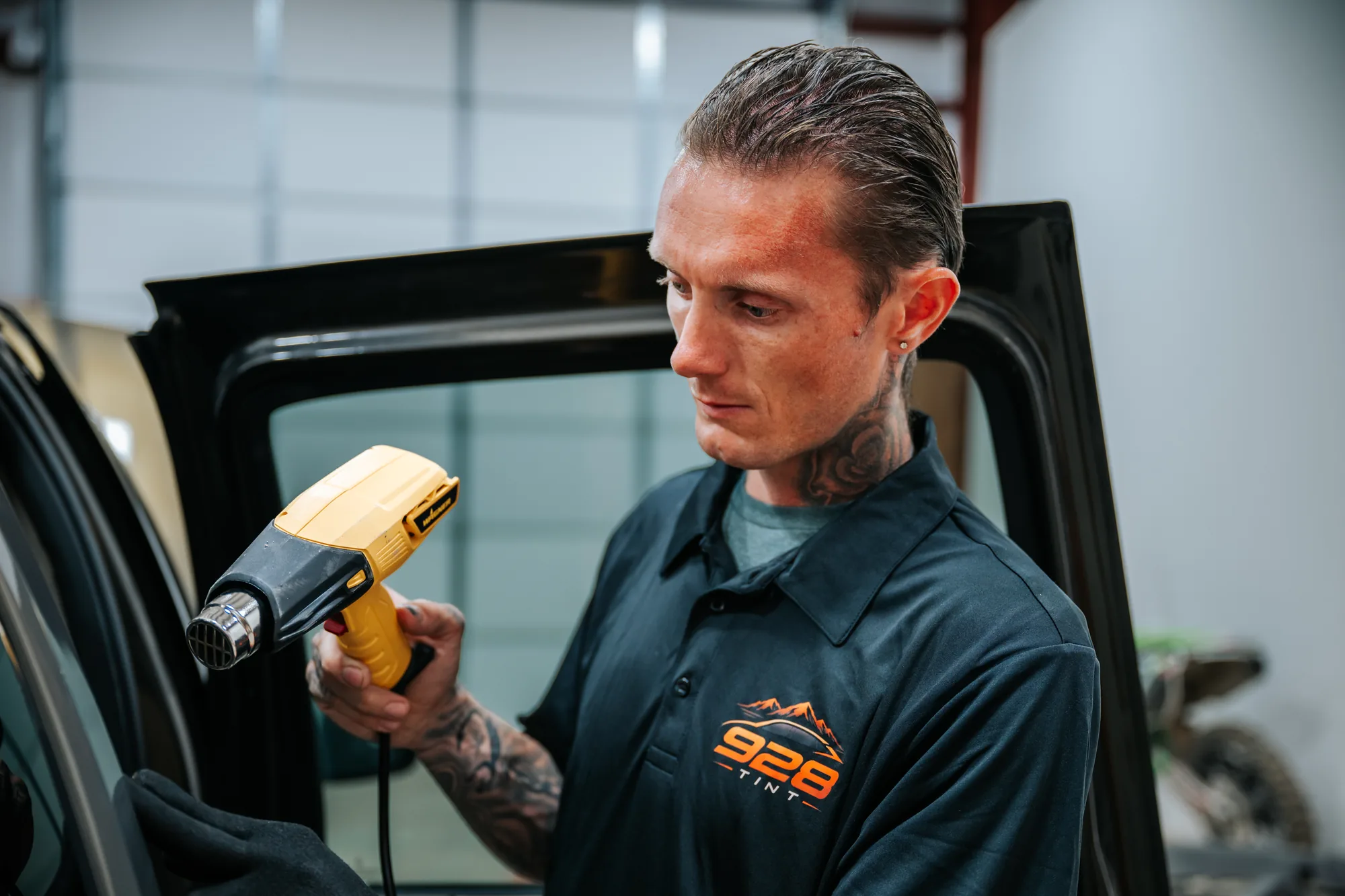 Jonny Martin heat-shrinking window film with a heat gun at 928 Tint
