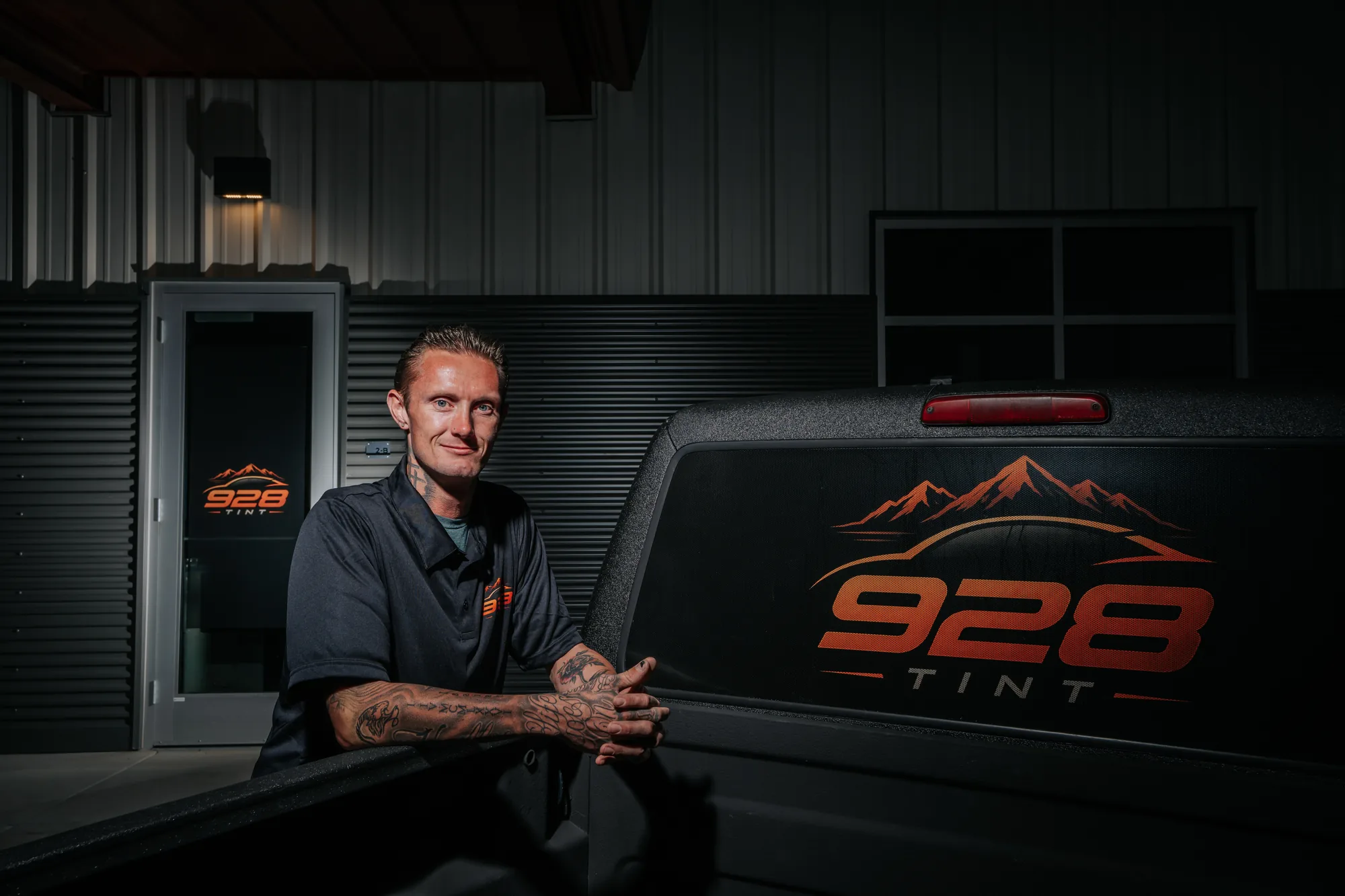Jonny Martin, owner of 928 Tint in Prescott Valley, leaning on a truck with the 928 Tint logo on the back glass