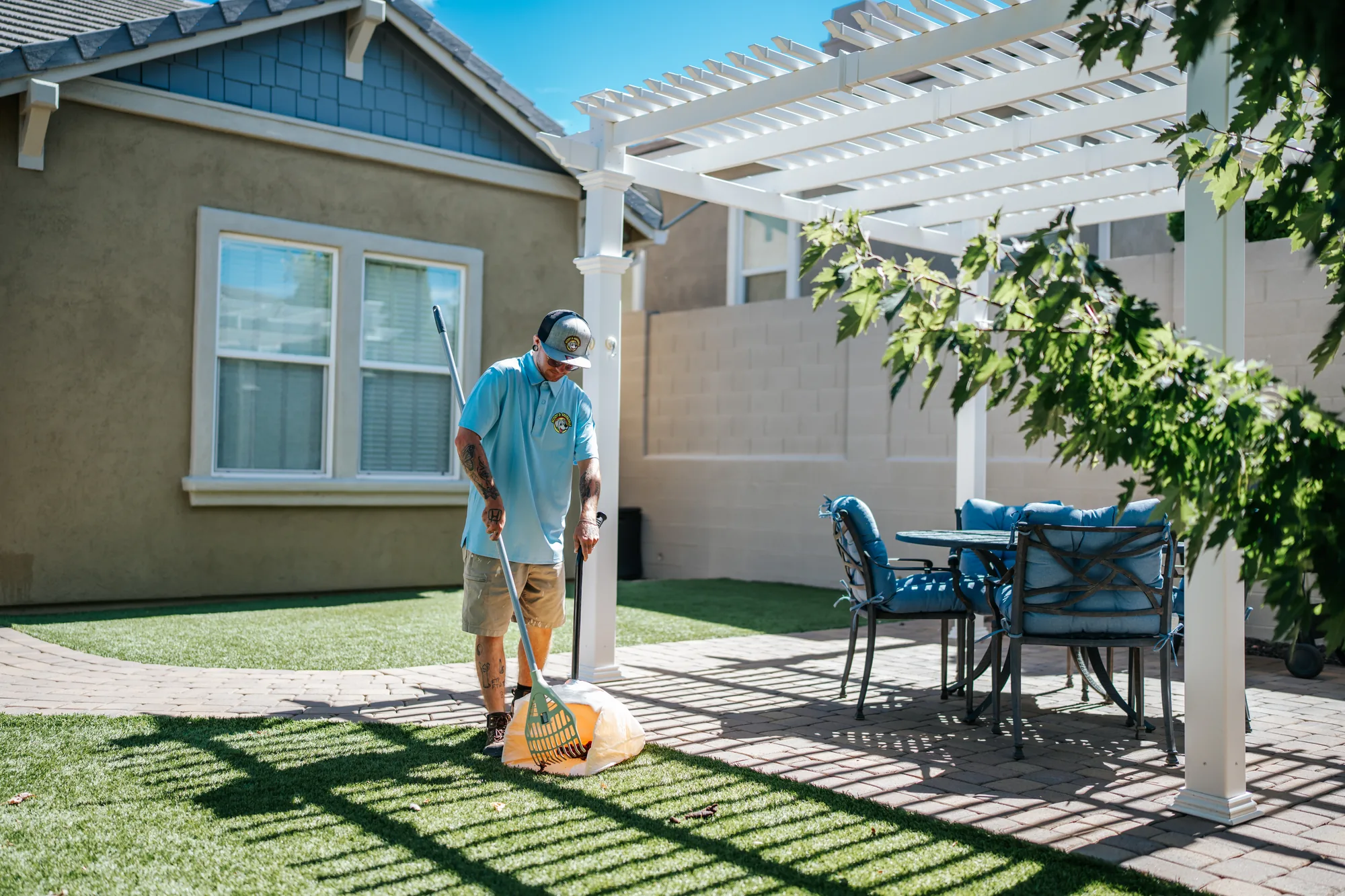 Scoop & Skedaddle technician doing a backyard pet waste cleanup beside a white pergola