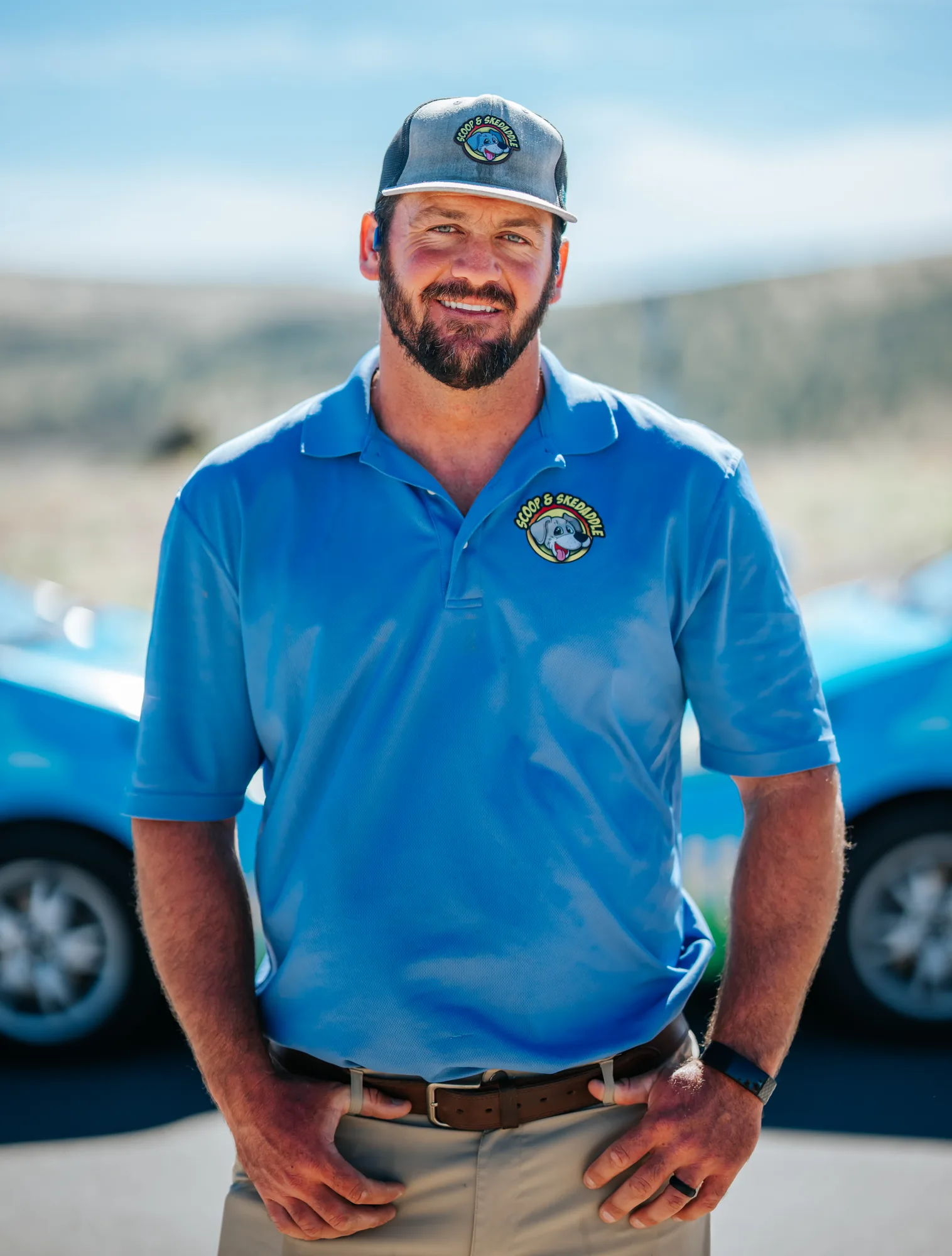 Portrait of a Scoop & Skedaddle crew member in a blue uniform polo and company cap