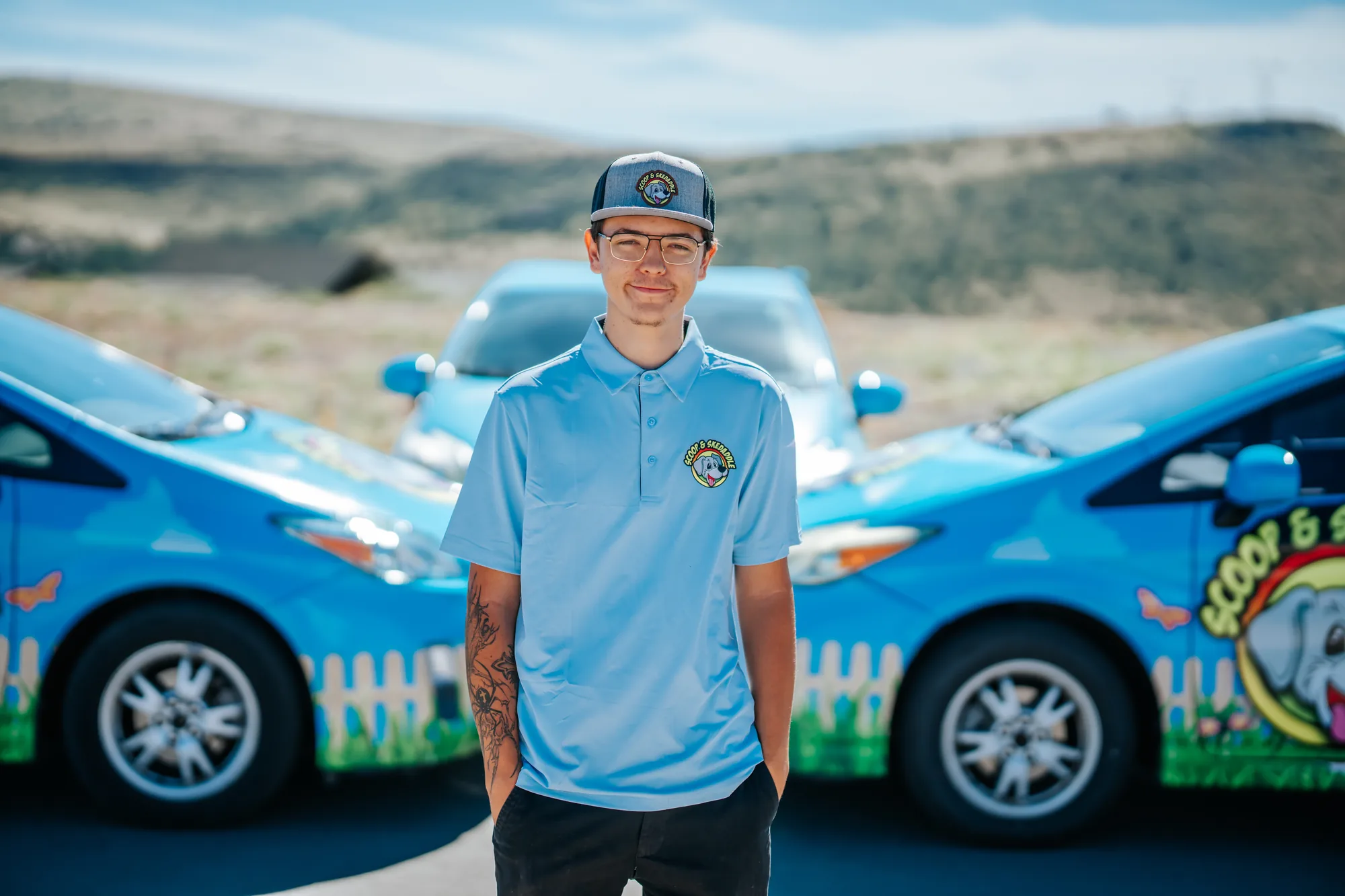 Portrait of a Scoop & Skedaddle crew member in glasses and a company cap