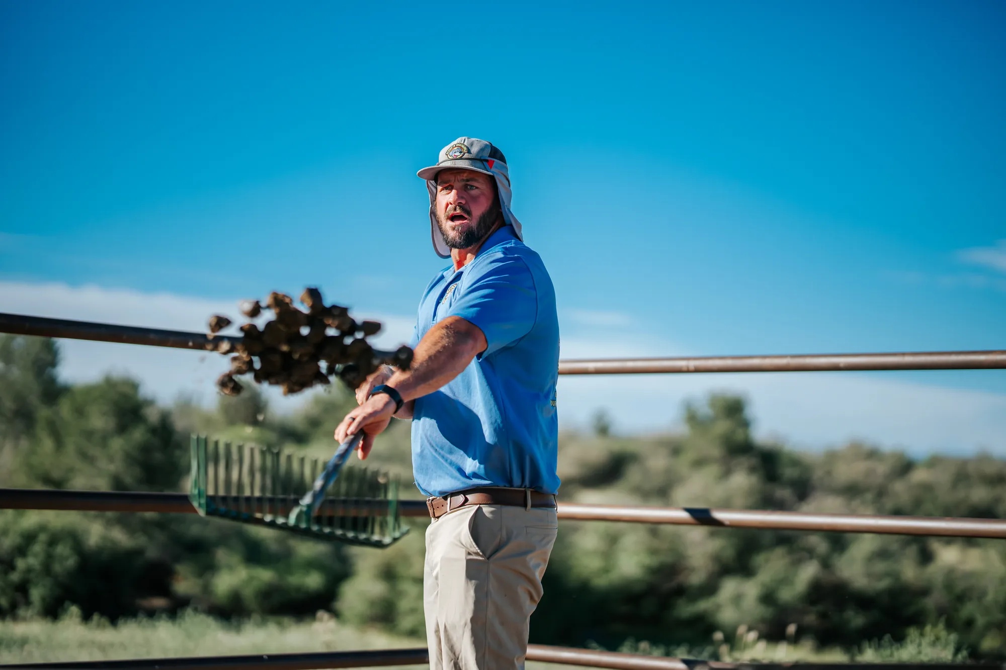 Scoop & Skedaddle team member tossing a forkful of manure while clearing a horse paddock