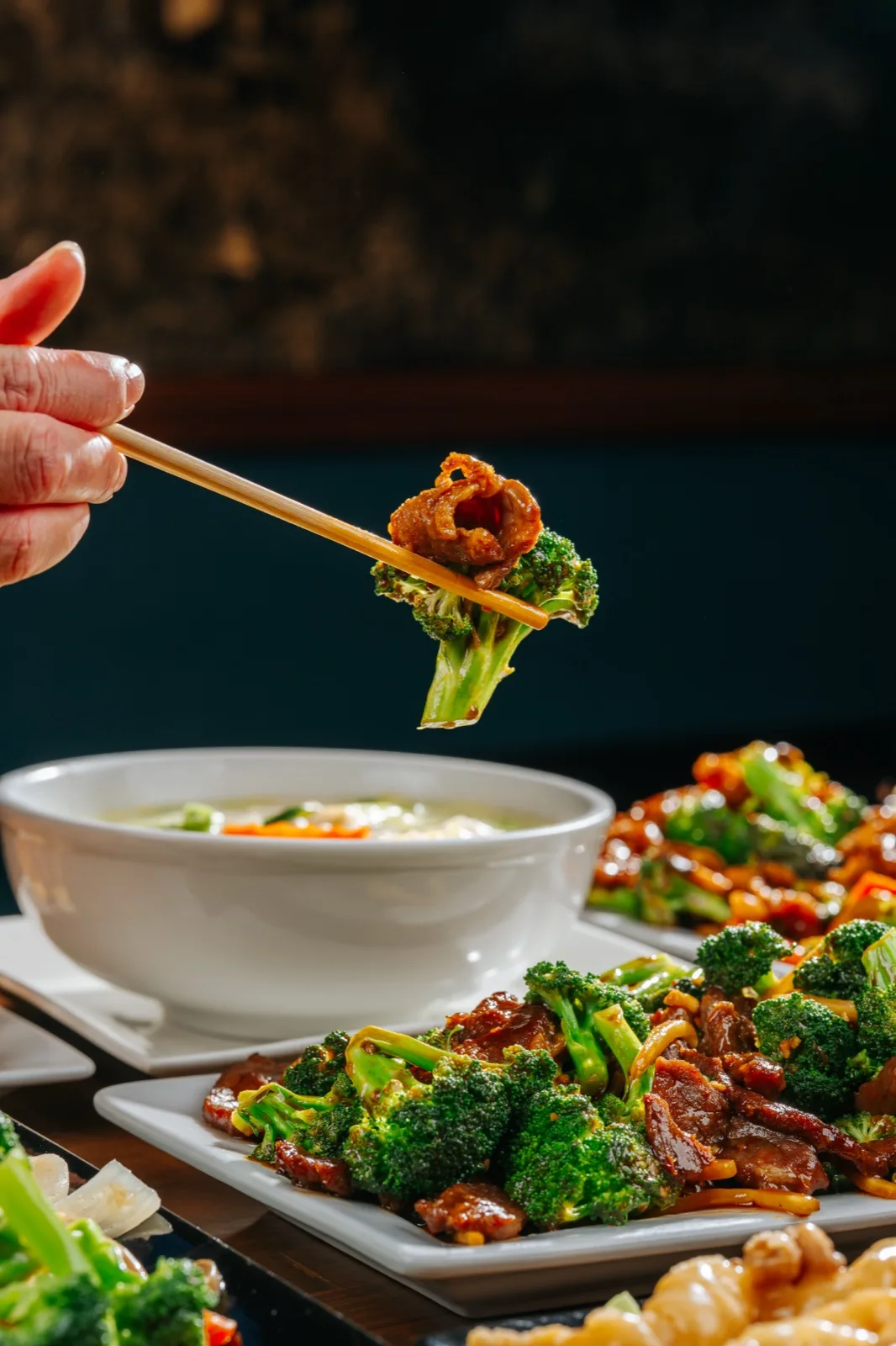 Hunan Chinese Restaurant, chopsticks lifting a glazed wok-fired bite, dramatic editorial lighting