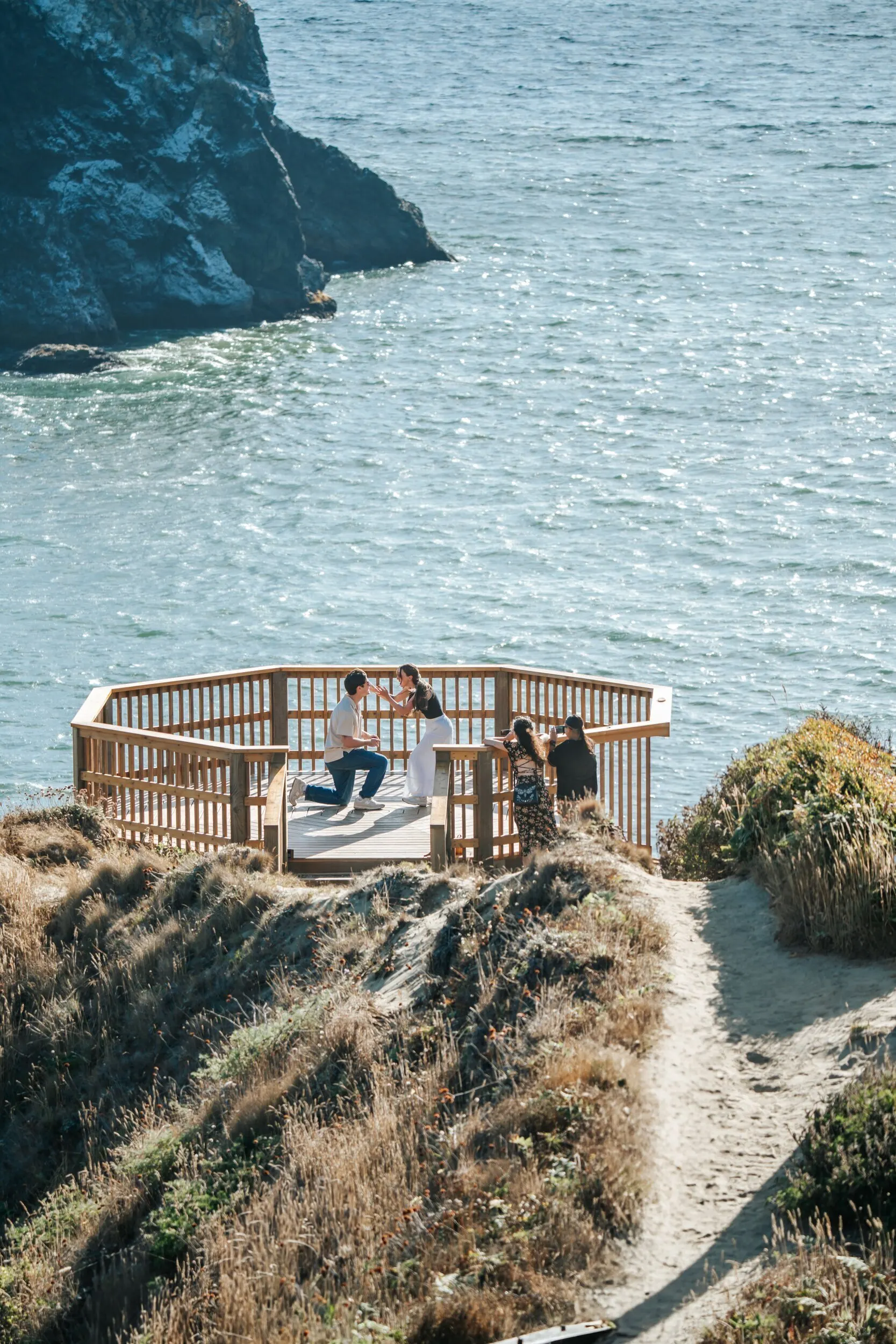 Couple at Trinidad Head with the lighthouse trail behind them