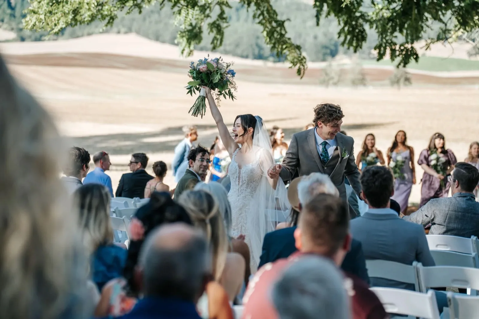 Bride raising her bouquet as guests celebrate. Fortuna wedding photography