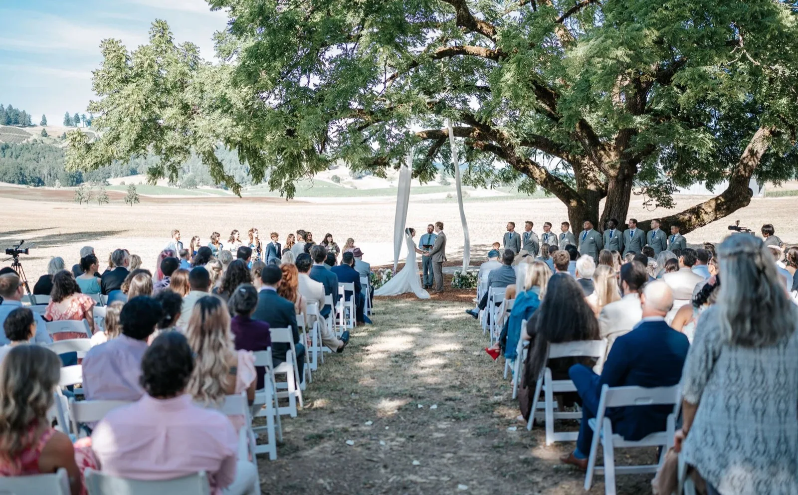 Outdoor ceremony under an oak tree with guests. Fortuna, California wedding
