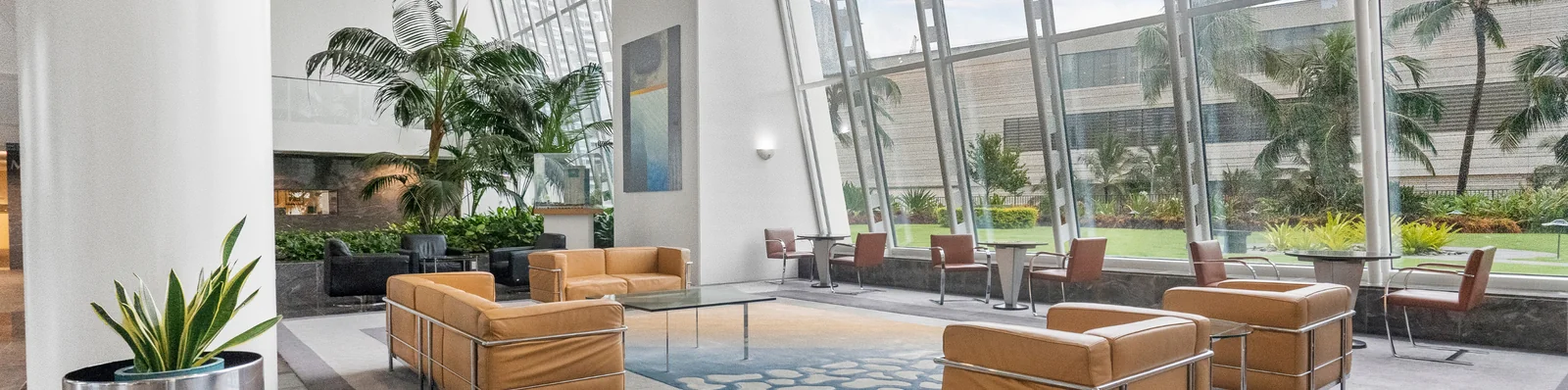 Modern hotel lobby with palm trees, mid-century lounge seating, and floor-to-ceiling windows (photo via Matterport partner materials)
